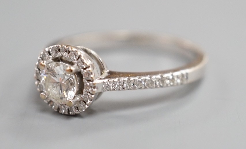 A modern 18ct white gold and single stone diamond ring with diamond chip circular setting and diamond chip set shoulders, from The Diamond Store, London